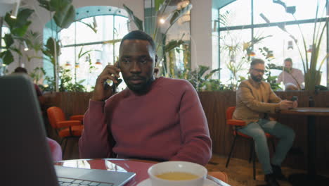 hombre de negocios negro hablando por teléfono en una cafetería