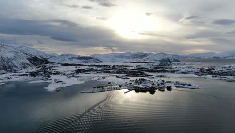 vista de drones en el área de tromsø en invierno volando sobre islas nevadas rodeadas por el mar en y molinos de viento en la montaña en noruega