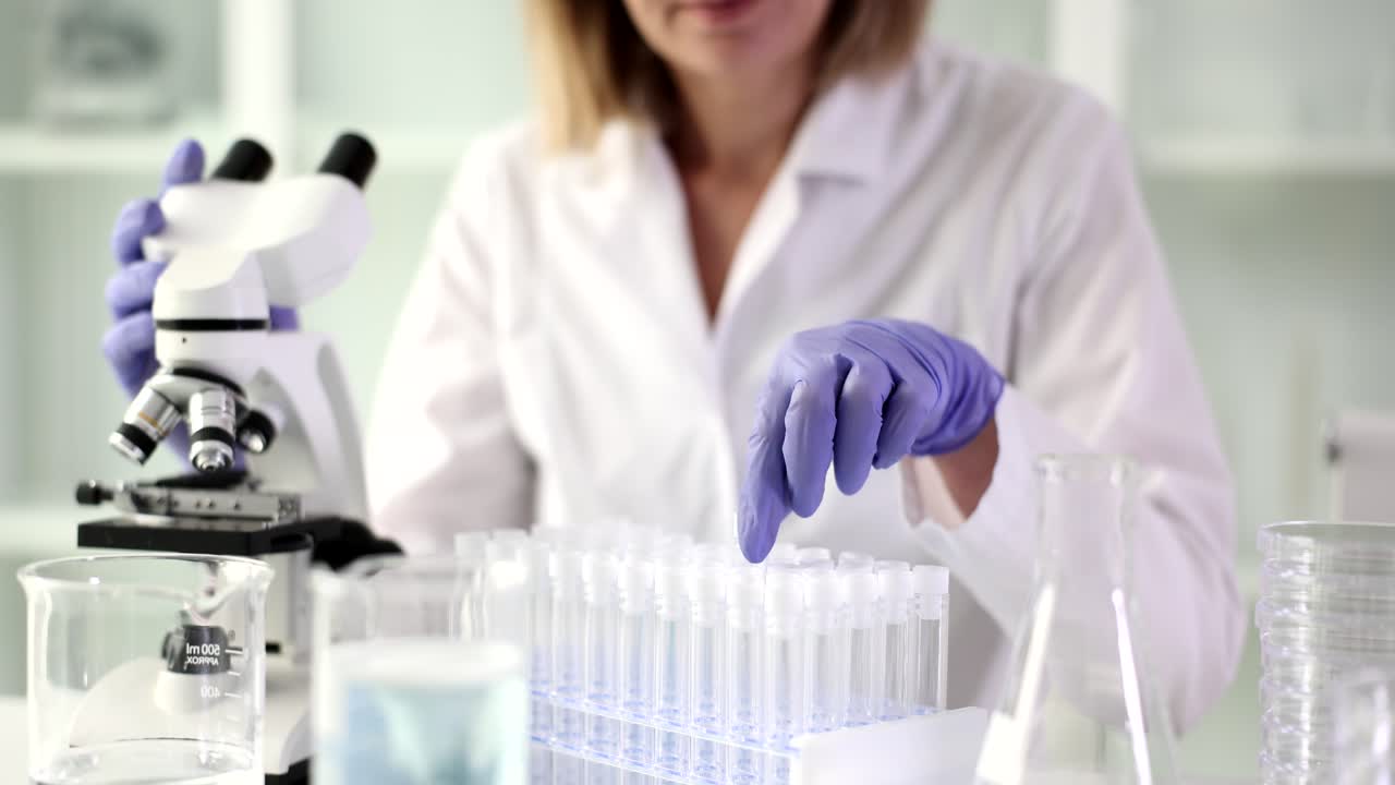 A scientist working in a laboratory with test tubes and a microscope