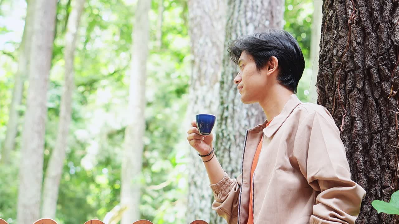 Thoughtful young asian man enjoying coffee break at cafe nature