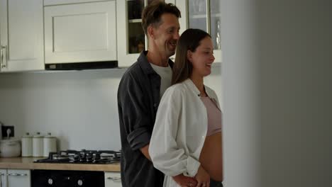 Happy-middle-aged-man-dancing-with-his-pregnant-wife-in-the-kitchen.-Happy-couple-husband-and-wife-expecting-a-baby-and-dancing-in-the-kitchen