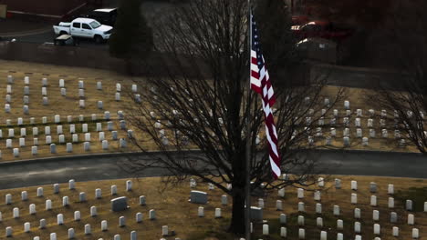 aerial orbiting shot of american flag at fayetteville national cemetery in arkansas