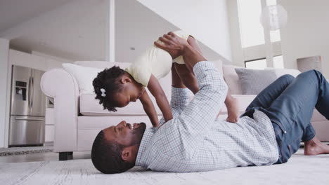 father playing with baby daughter lifting her in the air at home