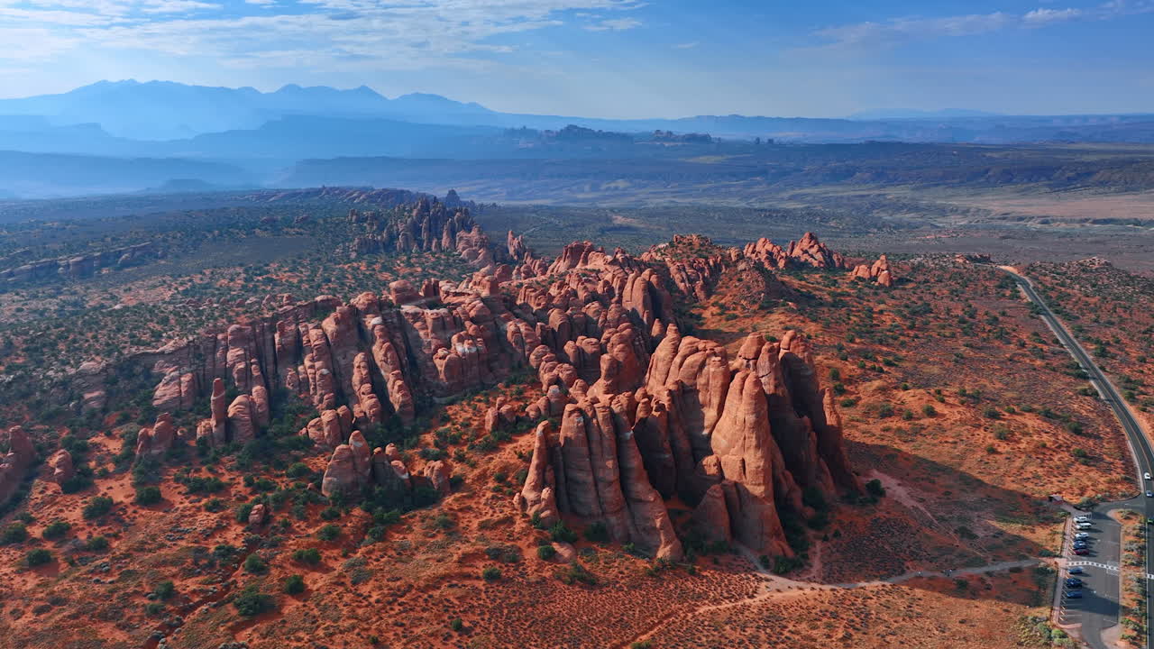 Allontanamento dal gruppo di splendide rocce crestate nel deserto. Silhouette nebbiose di montagne sullo sfondo. Arches National Park, Utah, Stati Uniti