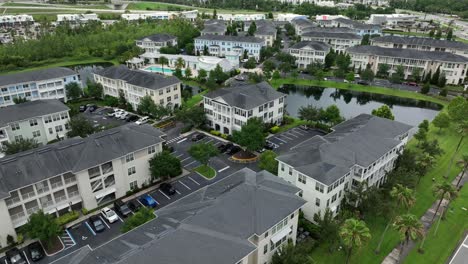 aerial flyover luxury apartment townhouses in florida, usa. private community swimming pool and pond in noble neighborhood of celebration town, united states. wide shot.
