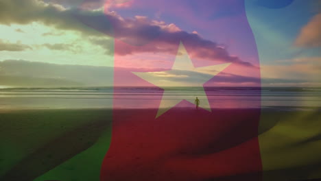 digital composition of waving cameroon flag against man walking on the beach