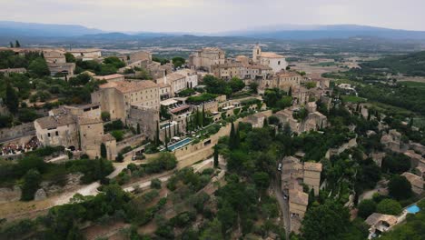 Toma-Aérea-De-Establecimiento-De-La-Aldea-De-Gordes-En-Una-Colina-Con-Edificios-Antiguos-En-Francia.