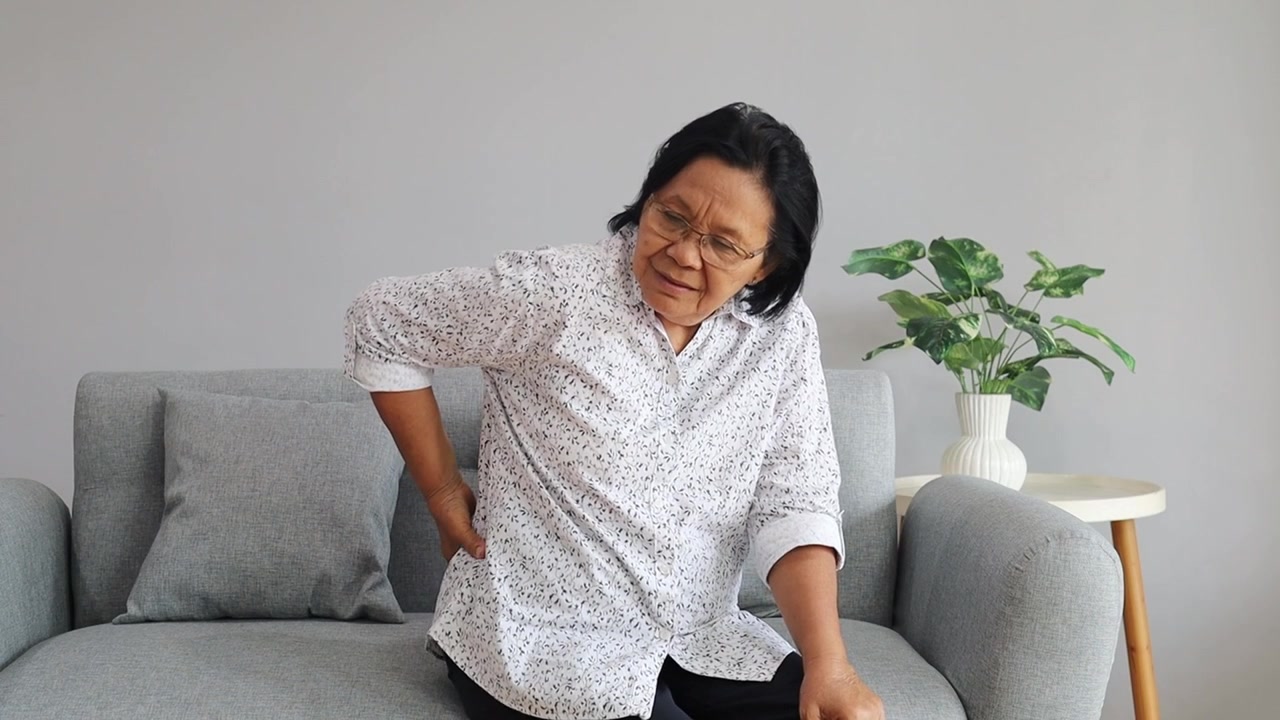 Asian Old woman suffering low back pain caused by spinal degeneration, ruptured discs, skeletal irregularities, arthritis or osteoarthritis chronic diseases concept