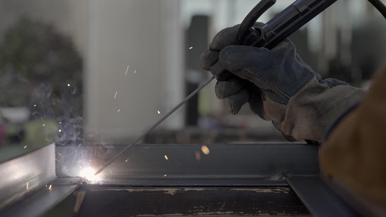 Hands of person welding metal object in close up slow motion shot