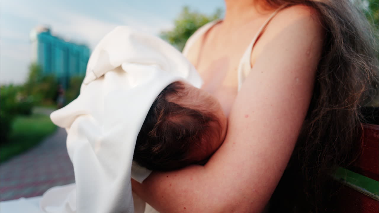 Close up of a mother holding her newborn in her arms outdoors during sunset