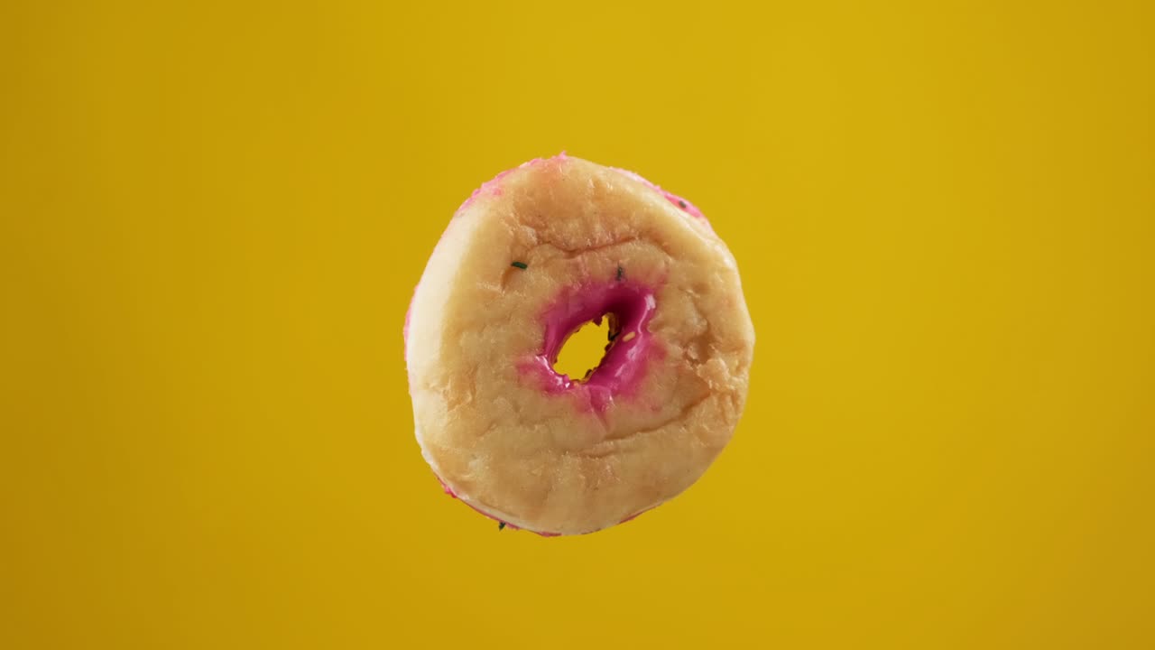 rosquilla salpicada de colores girando en fondo amarillo. concepto de panadería y comida.