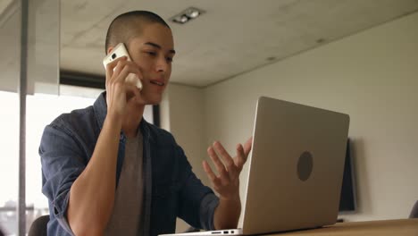 man talking on mobile phone while using laptop at home 4k