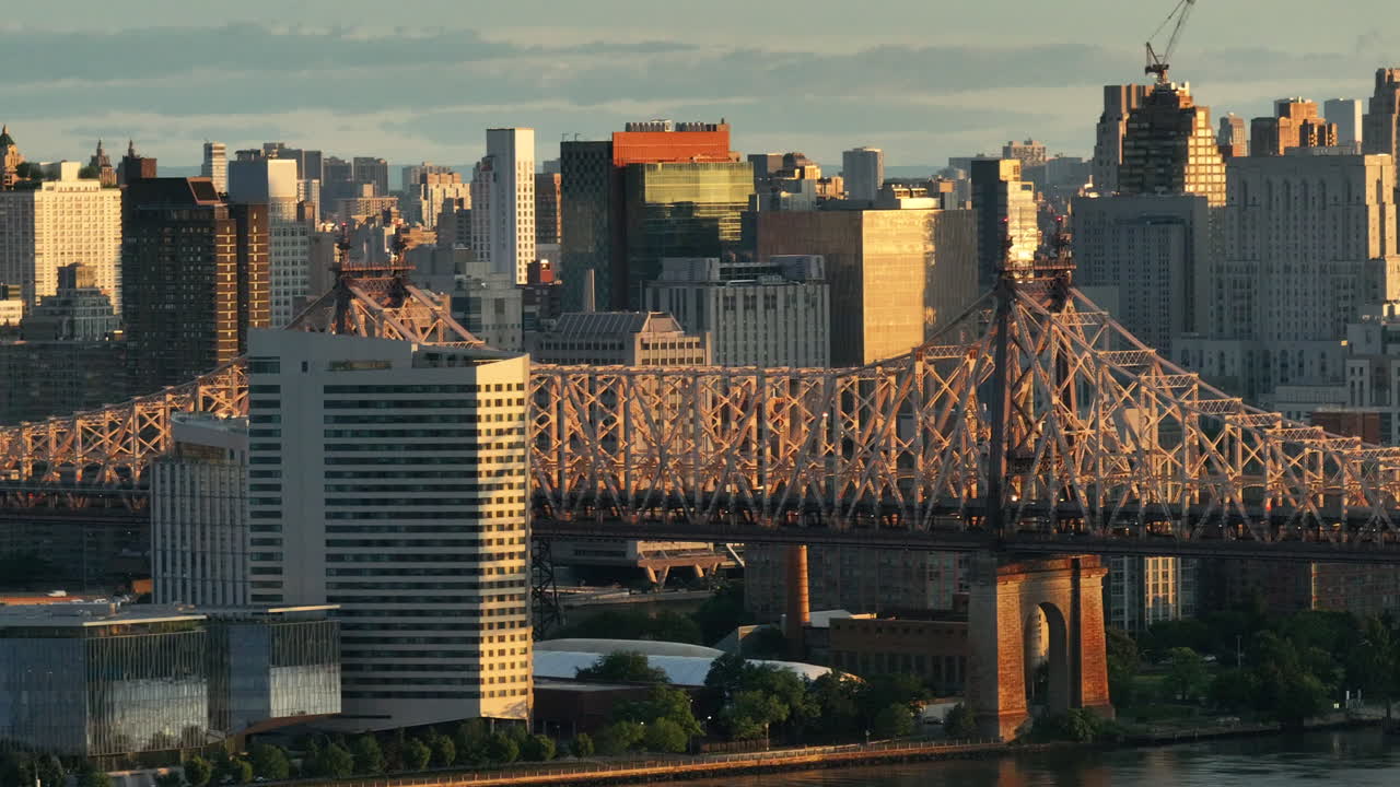 Aerial view of the Queensboro Bridge at sunrise. Shot along the East River with Roosevelt Island and Manhattan in the background