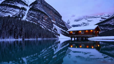 winter cabin on a frozen lake, majestic mountains in the background