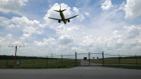 airplane passing overhead on approach to landing at airport on cloudy day