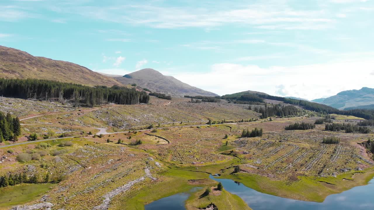 Bjergvej ved søbredden i det skotske højland på en solrig dag, drone.