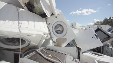 white discarded appliances dumped onto pile at disposal centre, slider