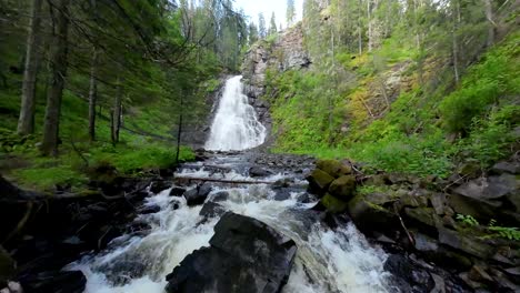 A-scenic-view-of-Flokofallet-waterfall-in-Norway,-surrounded-by-lush-green-forest-and-a-rushing-stream