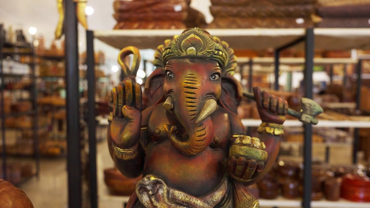 Una grande statua in legno intagliato del dio Ganesh dalla testa di elefante si erge tra scaffali di artigianato in un negozio in Sri Lanka. Le statue di Ganesh sono popolari tra i visitatori indù.