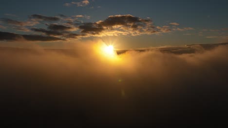 Vista-Aérea-Panorámica-Del-Sol-Sobre-Las-Nubes-En-Cámara-Lenta-Mientras-Algunas-Nubes-Pasan-Frente-Al-Sol