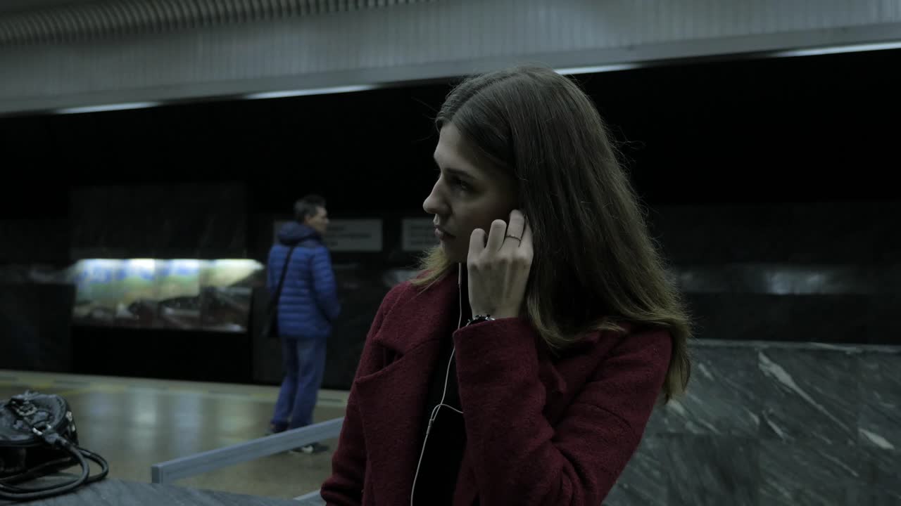mujer escuchando música en una estación de metro