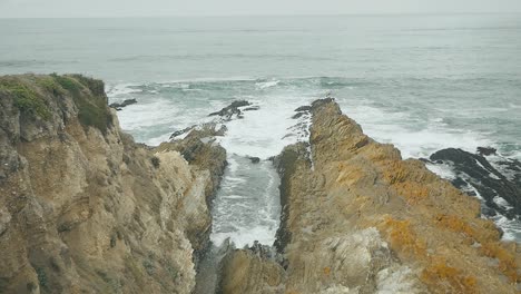 Slow-Motion-waves-coming-in-over-long-coastal-bluffs-on-overcast-summer-day