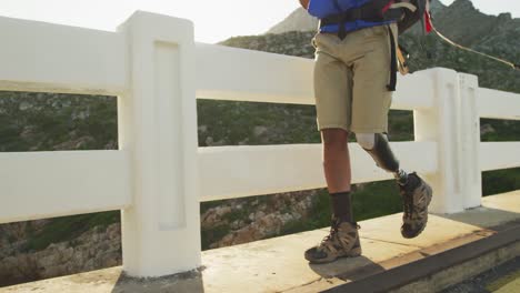 hombre de raza mixta con pierna protésica caminando por el lado de la carretera