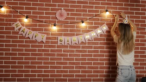 The-girl-decorates-the-room-for-the-holiday-with-garlands-and-flags