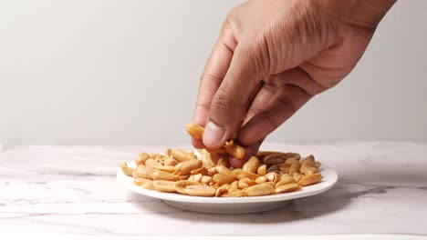 Side view of hand pick peanuts from a plate ,