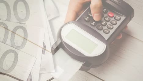 Animation-of-euro-banknotes-falling-over-hand-of-caucasian-man-holding-payment-terminal