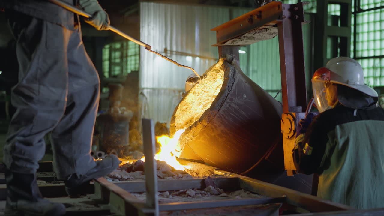 Foundry worker tilting ladle to pour molten metal with flames and sparks