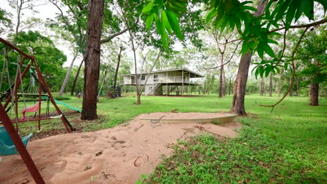 propiedad de superficie rural residencial con columpio de patio de recreo antiguo y pozo de caja de arena en un gran patio al aire libre cubierto de hierba