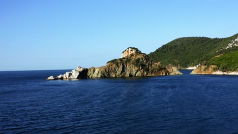 在陽光明<unk>的日子中,從空中看到一個小岩石島和背景的陸地