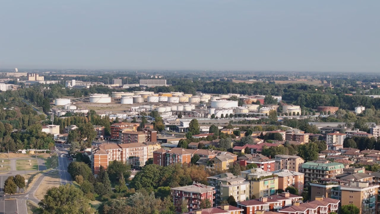 La raffineria Tamoil domina il distretto industriale vicino a Piazzale Caduti del Lavoro 30, Cremona, Lombardia, Italia, con edifici residenziali e strade alberate, inquadratura statica che passa a un allontanamento.