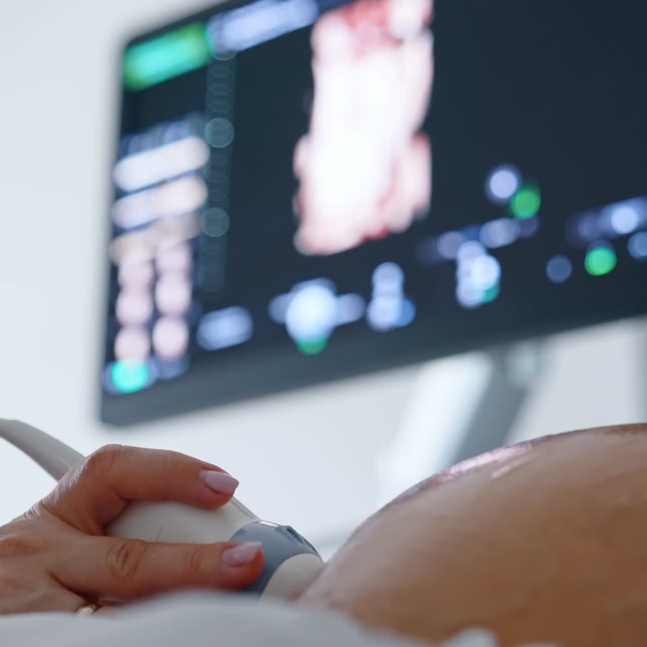 Obstetrician's hand using ultrasound equipment to check the development of a fetal child. Close up. Black screen at backdrop in blur