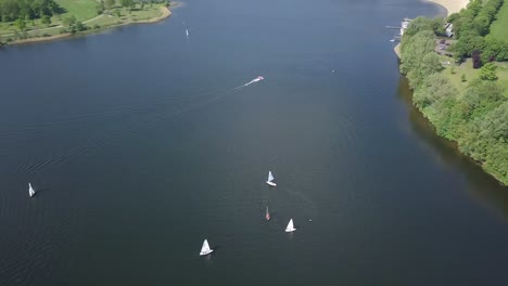 aerial footage of the sailboats with the speed boat moves fast at the lake in 4k