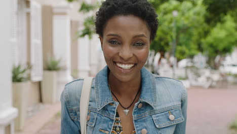 portrait of happy african american woman commuter laughing cheerful looking at camera wearing denim jacket in city enjoying lifestyle