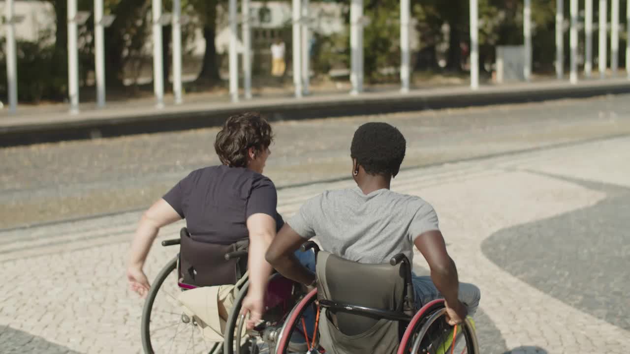 vista trasera de una pareja que usa sillas de ruedas caminando juntos