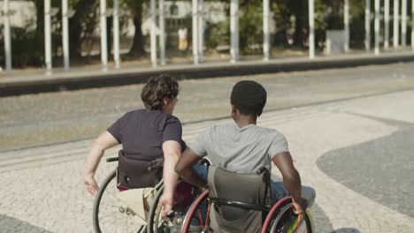 rear view of couple using wheelchairs walking together