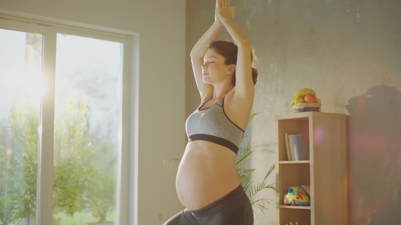 беременная женщина занимается йогой дома