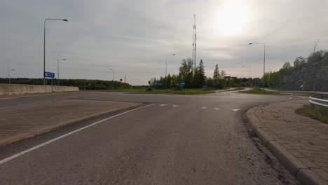 Cars-drive-along-the-road-with-green-grass,-trees,-and-road-signs