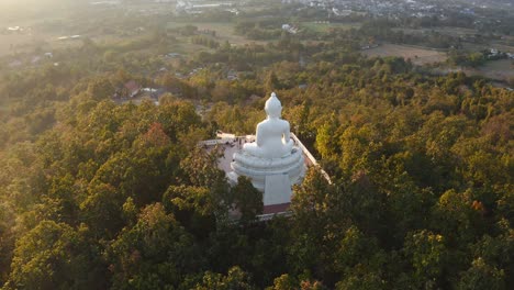 vista aérea cinematográfica de 4k de la gran estatua blanca de buda pai en medio del bosque al atardecer