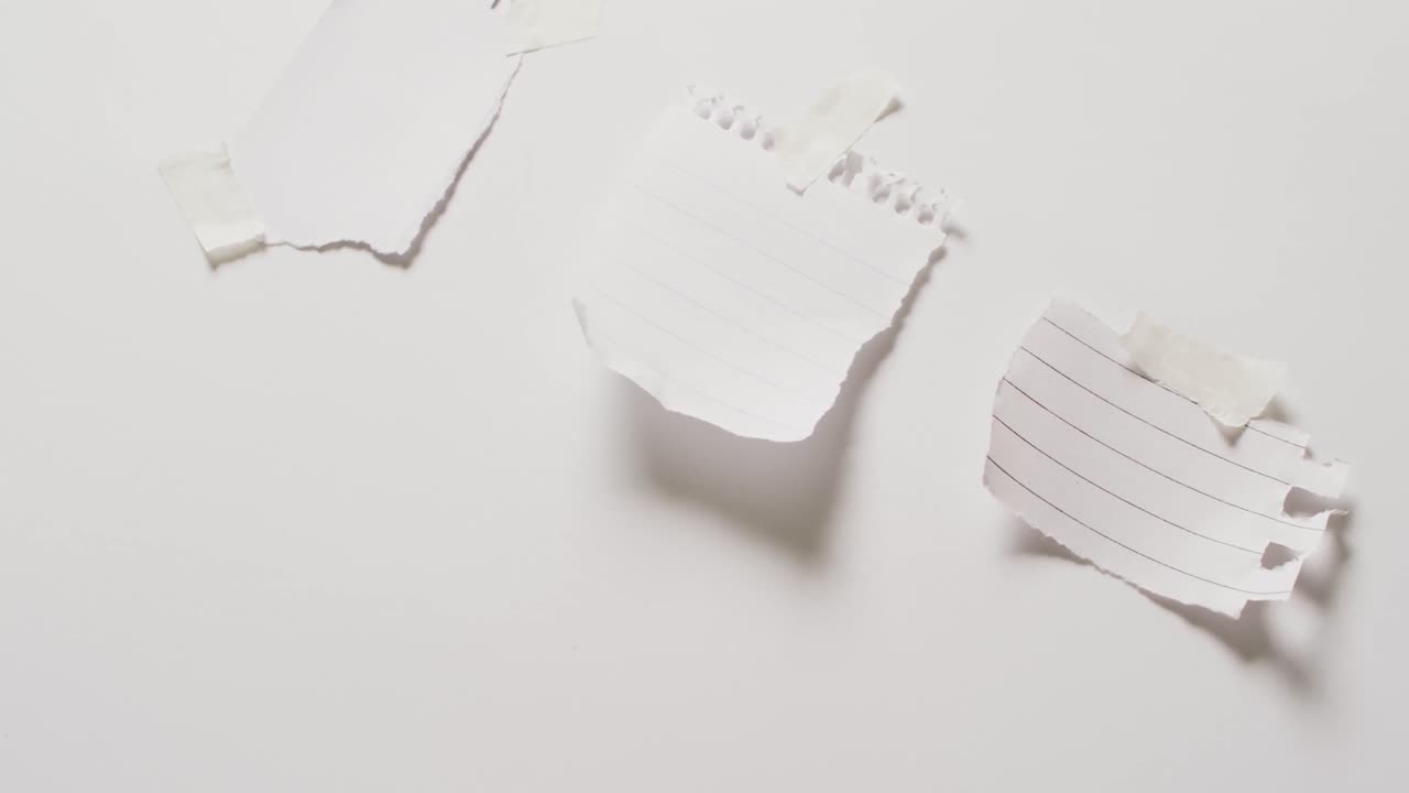 video de un primer plano de tres trozos de papel con espacio de copia pegado en un fondo blanco
