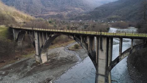 old concrete arch bridge over a river in mountainous valley