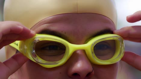 attractive female hispanic swimmer puts on her goggles to prepare to swim