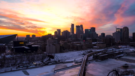 Drohnen-Hyperlapse-Eines-Strahlenden-Sonnenuntergangs-Hinter-Den-Wolkenkratzern-Von-Minneapolis-Mit-Dem-Mississippi-Im-Vordergrund