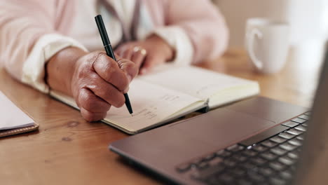 elderly woman writing in a notebook at a desk
