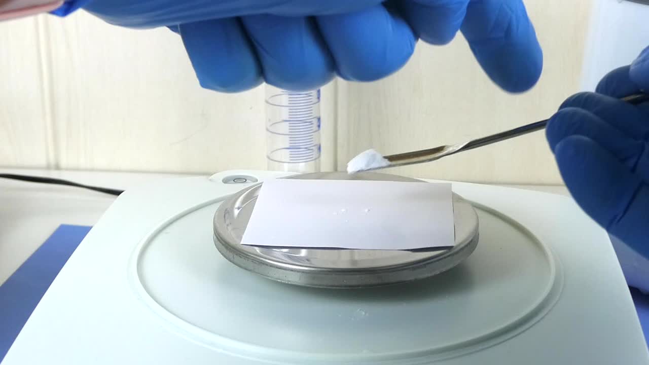 Close-up of a laboratory technician's gloved hands performing a quality control test on hyaluronic acid powder in a cosmetic laboratory.