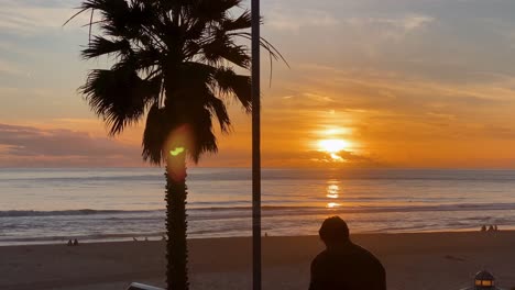 joven en el espacio de estacionamiento observando el hermoso paisaje dorado del atardecer sobre la playa