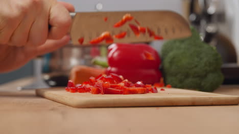 la ama de casa corta pimienta roja fresca en una tabla de madera con un cuchillo